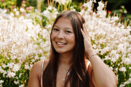 Woman in sundress posing in front of wildflowers.