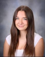 Brunette woman in white top with gray background.
